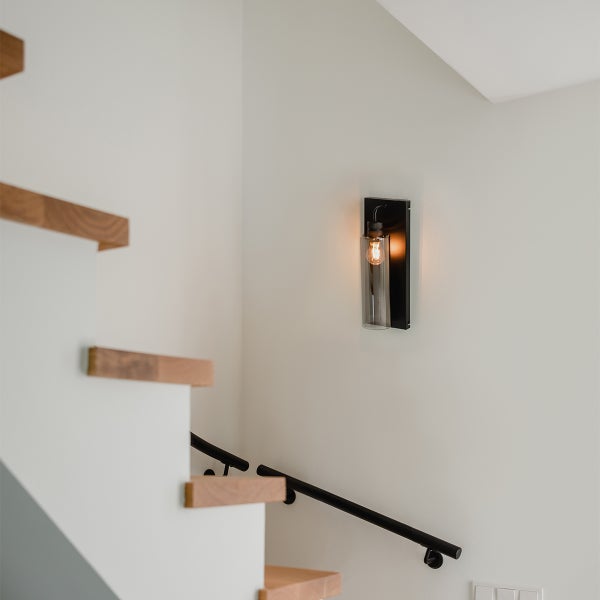 Wandleuchte aus Metall und Glas neben einer Treppe.
