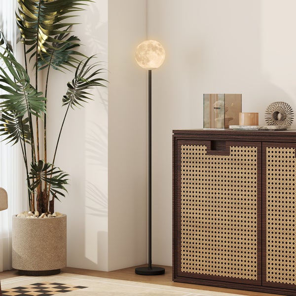 Innenraum mit Stehlampe in Mondform, Kommode mit dekorativen Objekten und Zimmerpflanze im Topf.