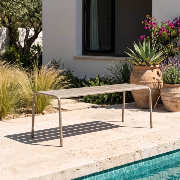 Moderne Gartenbank aus Metall mit Lattenrost auf einer hellen Steinterrasse neben einem Pool, umgeben von mediterranen Pflanzen in Tontöpfen.