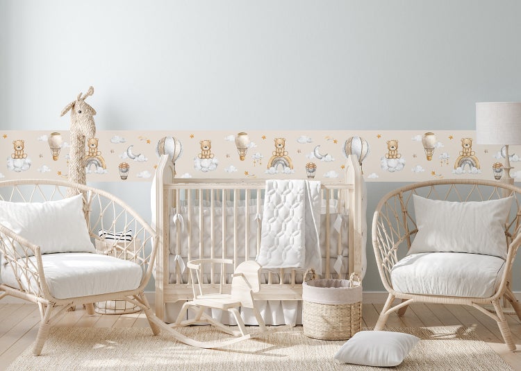 Selbstklebende Bordüre für das Kinderzimmer mit Teddybären, Regenbögen und Heißluftballons in einem hellen Babyzimmer mit Holzmöbeln.