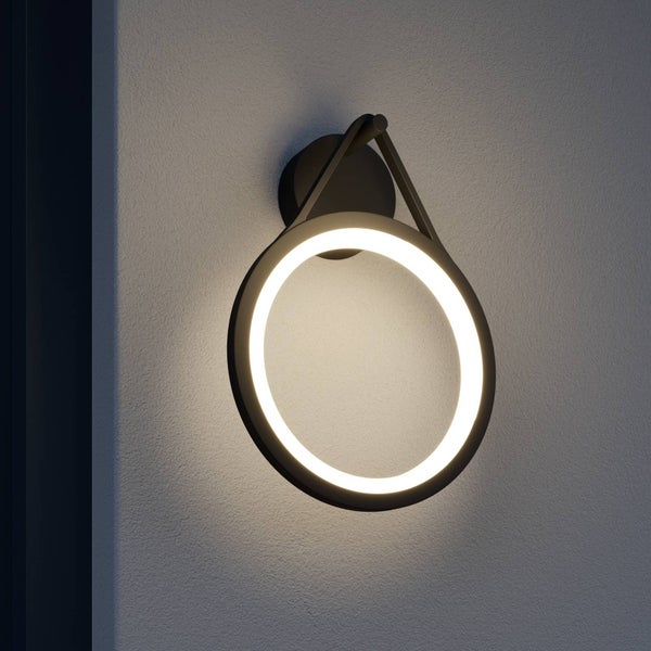 Moderne ringförmige LED-Außenwandleuchte mit schwarzer Aufhängung an einer strukturierten Wand.