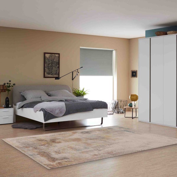 Moderner Teppich mit abstraktem Muster in einem hellen, aufgeräumten Schlafzimmer mit Bett und Kleiderschrank.