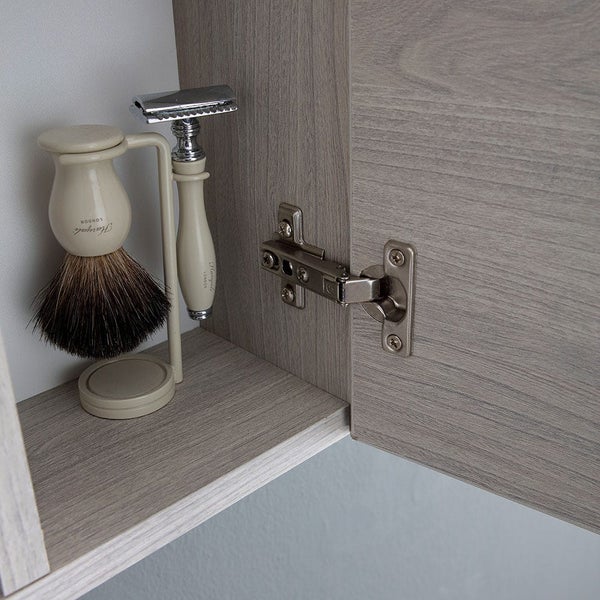 Badezimmerschrank mit Holzoptik, Metallscharnier an der geöffneten Tür, Innenraum mit Rasierpinsel und Nassrasierer auf einem Halter.