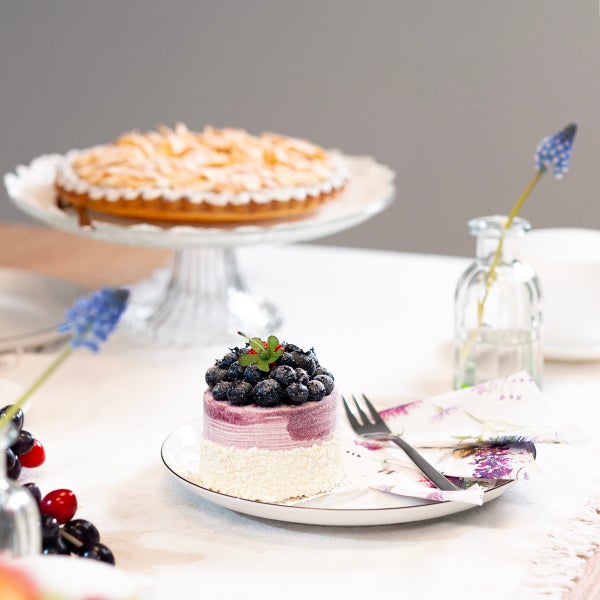Dekorativer Tisch mit Kuchen und Törtchen auf Tellern