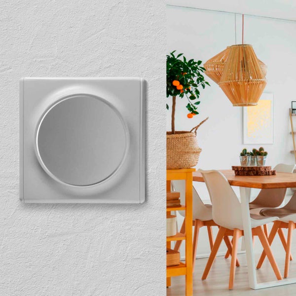 Ein runder Unterputz Drehdimmer an einer strukturierten Wand neben einem hellen und modern eingerichteten Esszimmer.