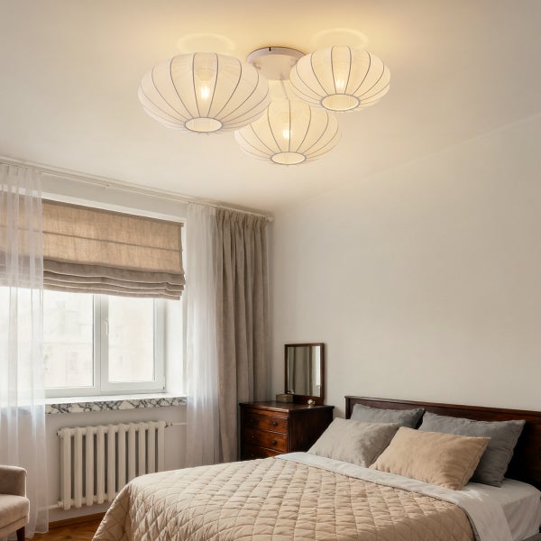 Dreiflammige Deckenleuchte mit weißen, gerippten Schirmen in einem hellen, gemütlichen Schlafzimmer mit Holzbett und Vorhängen.
