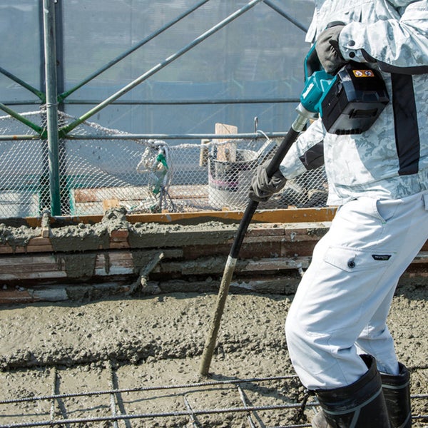 Ein Bauarbeiter verdichtet Beton mit einem Betonrüttler.