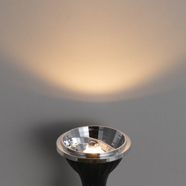 LED-Reflektorlampe mit verchromtem Gehäuse, die einen warmweißen Lichtkegel an eine Wand wirft.