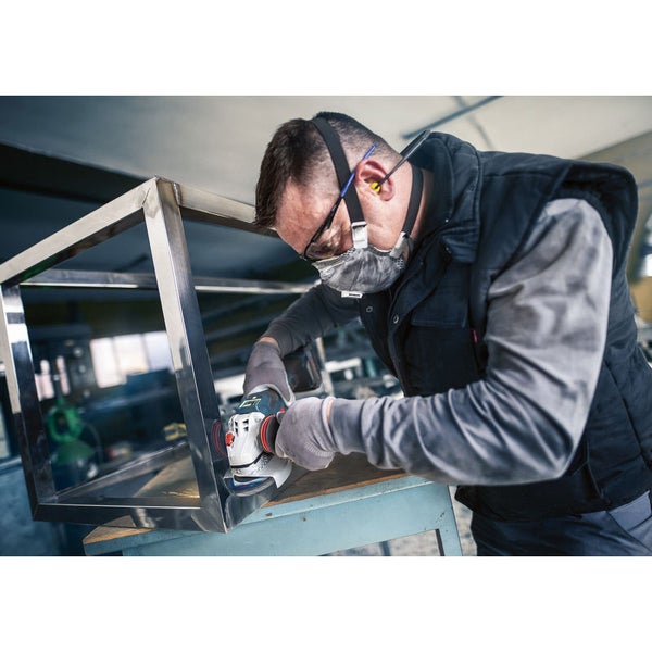 Handwerker schleift Metallrahmen mit Winkelschleifer. Persönliche Schutzausrüstung wird getragen.