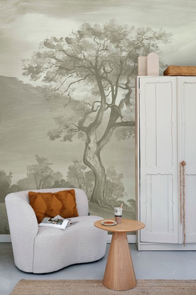 Helles Wohnzimmer mit Baumtapete, Sessel, Holztisch und weißem Schrank