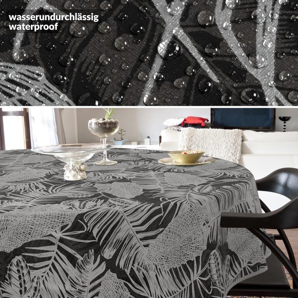 Runde, wasserundurchlässige Tischdecke mit modernem tropischem Blattmuster in Schwarz und Grau; Detail zeigt Wassertropfen auf der Oberfläche.