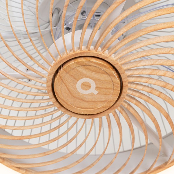 Nahaufnahme eines Deckenventilators mit spiralförmigen Holzlamellen und einer zentralen Holzabdeckung mit Q Logo.