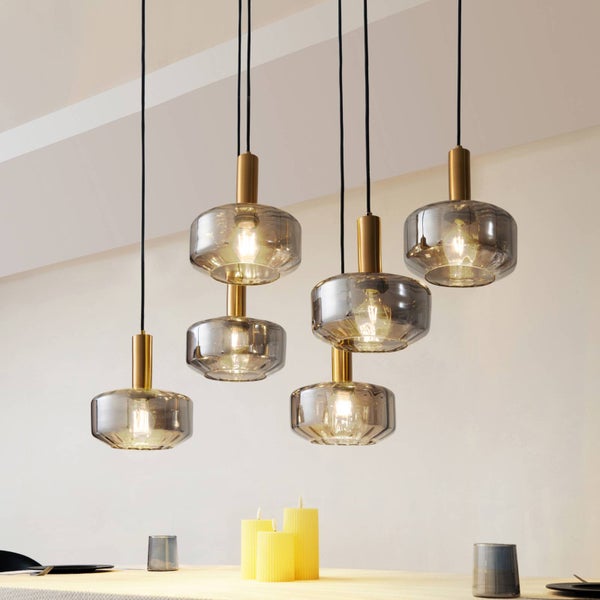 Sechsflammige Pendelleuchte mit rauchfarbenen Glasschirmen und goldfarbenen Metallfassungen über einem hellen Tisch montiert.