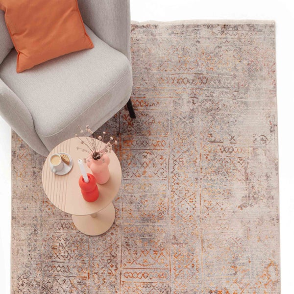 Vintage-Teppich mit orientalischem Muster in einer Wohnzimmerszene mit grauem Sessel und Beistelltisch.