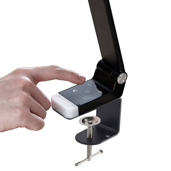 Eine Hand bedient das Touch-Bedienfeld einer schwarzen Schreibtischleuchte mit Schraubklemme.