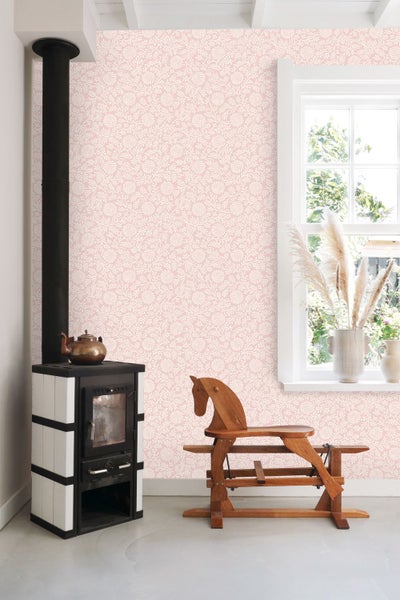Rosa Tapete mit feinem floralem Muster in einem hellen Zimmer mit Kaminofen, Fenster und Holzschaukelpferd.