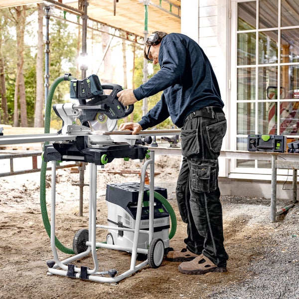 Ein Mann arbeitet mit einer Akku-Kapp- und Gehrungssäge von Festool auf einer Baustelle.