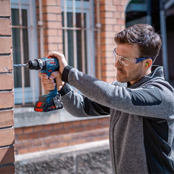 Handwerker bohrt mit einer Akku-Bohrmaschine ein Loch in eine Holzwand.