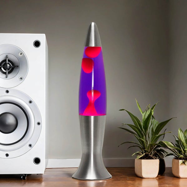 Lavalampe mit rotem Wachs in lila Flüssigkeit neben Lautsprecher und Zimmerpflanzen