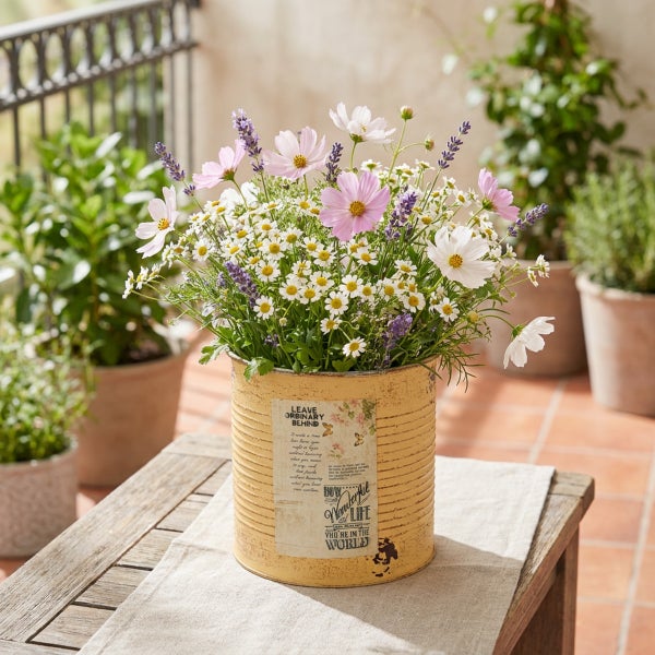 Blumenstrauß aus Kosmeen, Kamille und Lavendel in einem dekorativen Metallübertopf im Vintage Stil auf einem Holztisch.