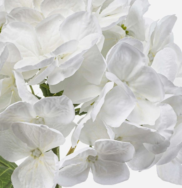 Künstliche Blume mit weißen Blütenblättern und grünen Blättern.