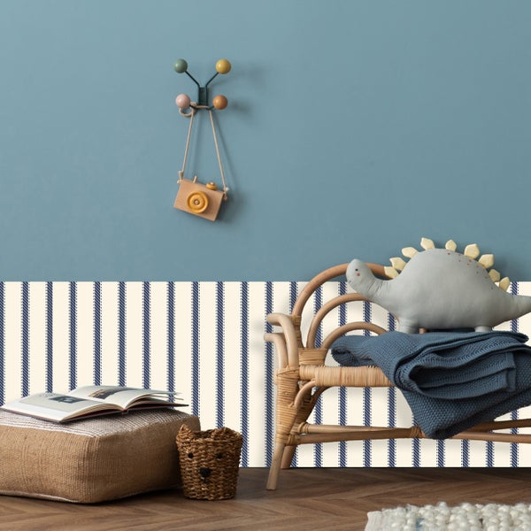 Dekoratives Kinderzimmer mit Rattanmöbeln, Spielzeug und gestreifter Tapete für eine gemütliche Atmosphäre.