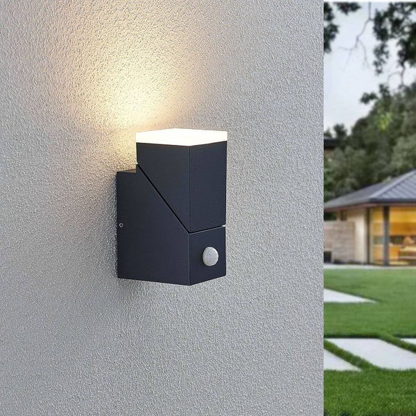 Moderne Außenwandleuchte in Anthrazit mit Bewegungsmelder an einer Hauswand, strahlt Licht nach oben ab.