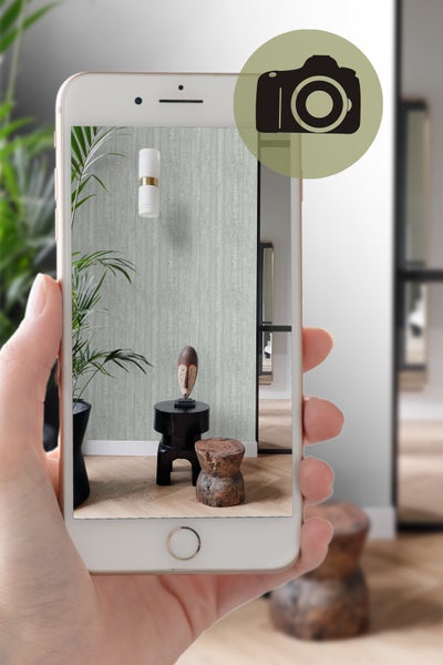 Smartphone zeigt ein mit einer gemusterten Tapete dekoriertes Zimmer.