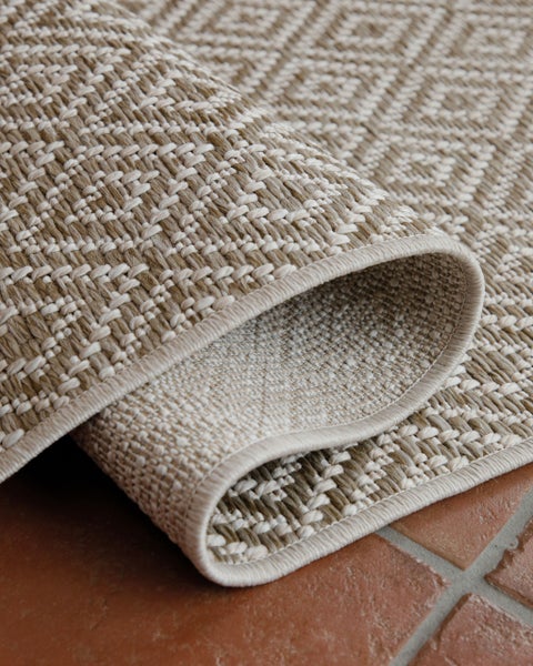 Flachgewebter Teppich mit Rautenmuster in Beige und Creme, Detailaufnahme der Oberflächenstruktur und Kante.