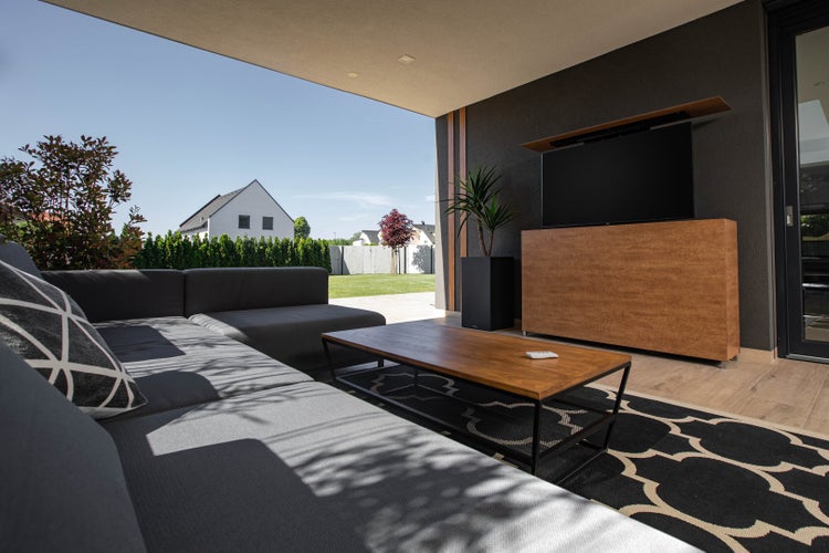 Moderne Terrasse mit grauer Sofagarnitur, Couchtisch und Medienmöbeln