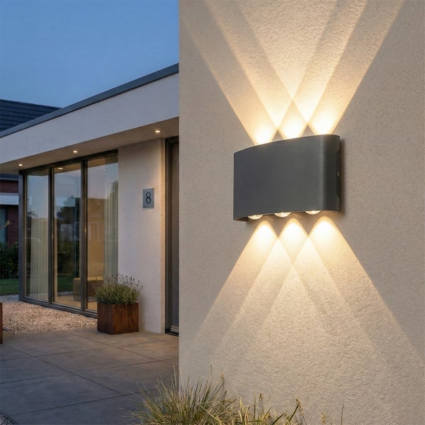 Moderne Außenwandleuchte in Anthrazit an einer Hauswand, die drei Lichtstrahlen nach oben und unten wirft, neben einem Hauseingang.