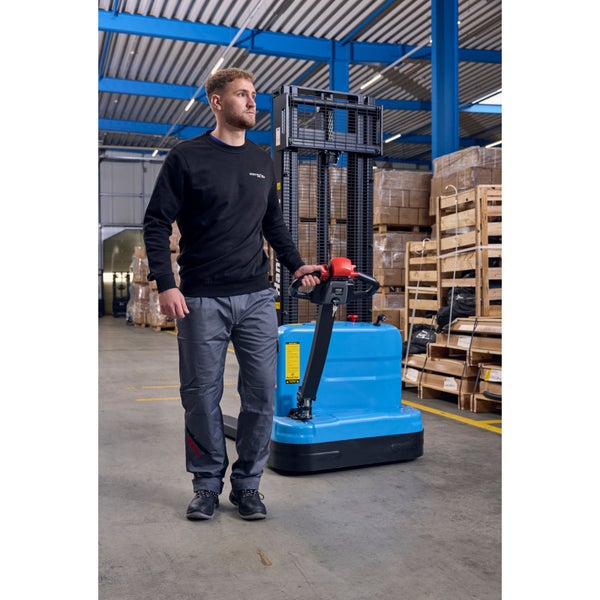 Ein Mann bedient einen blauen elektrischen Hochhubwagen in einem Lagerhaus mit Regalen und Paletten.