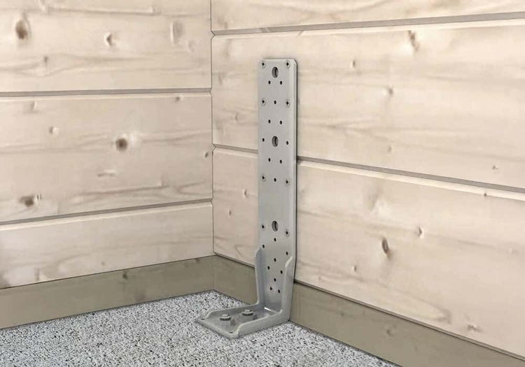 Ein Schwerlast-Winkelverbinder aus Metall ist an der Basis einer Holzwand aus waagerechten Brettern montiert.