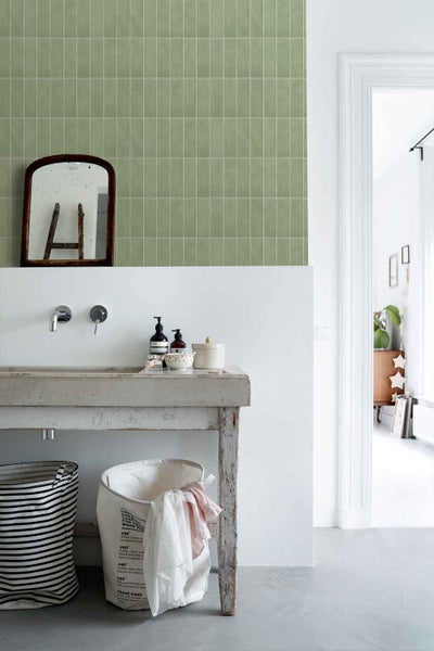 Badezimmer mit Wandfliesen im Hochformat an der Waschbeckenwand, kombiniert mit einem rustikalen Betonwaschtisch und einem hängenden Spiegel.