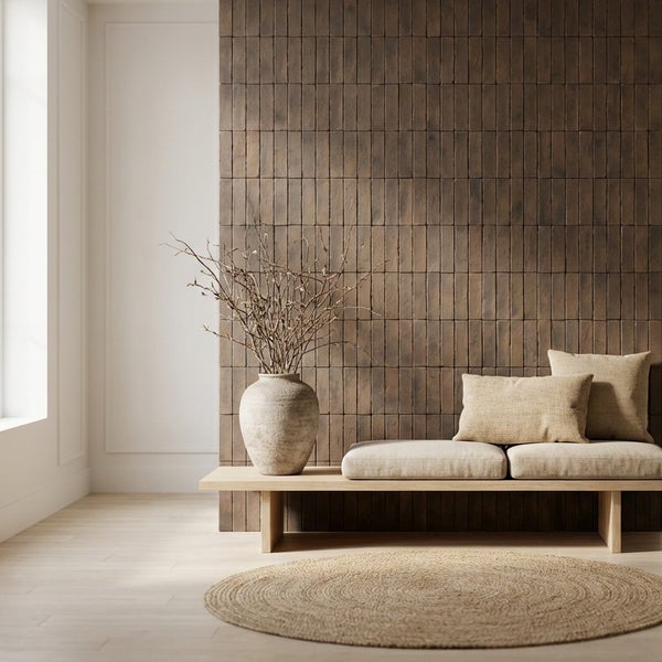 Wohnraum mit Wandfliesen in Ziegeloptik, schlichter Holzbank mit Kissen, Vase mit Zweigen und rundem Teppich im minimalistischen Stil.