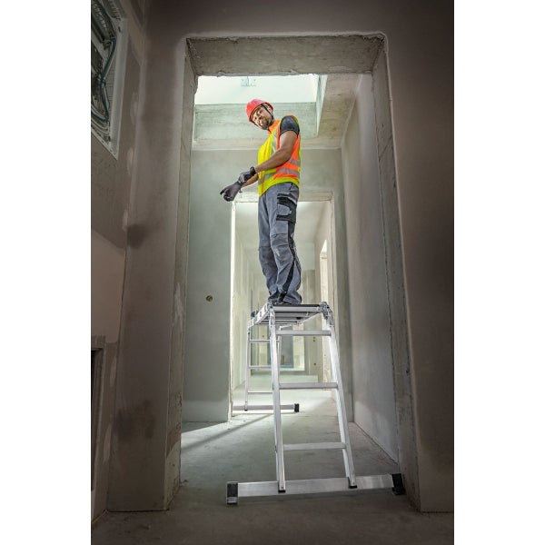 Handwerker auf einer Aluminium-Arbeitsbühne in einem Rohbau-Flur.