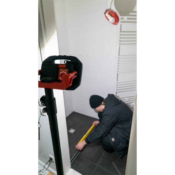 LED-Baustrahler mit Powerbank-Funktion lädt eine kleinere Leuchte über ein USB-Kabel auf einem Holzboden auf.