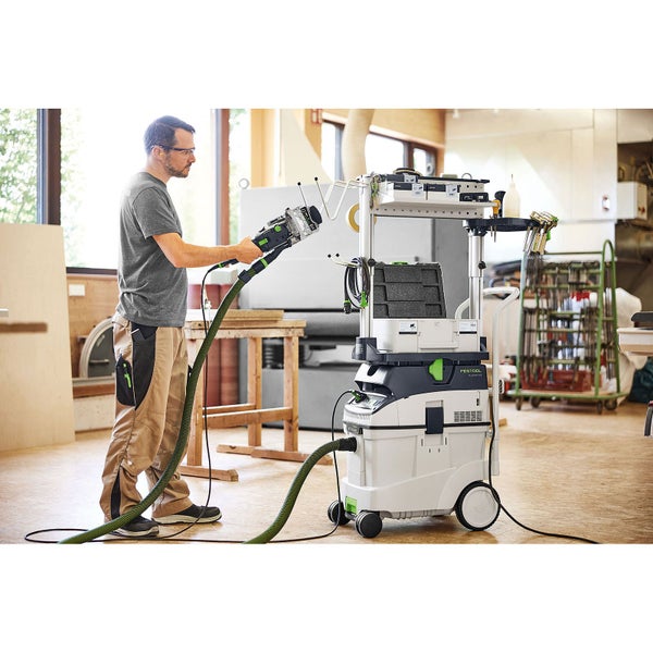 Handwerker nutzt Festool Absaugmobil mit Workcenter und angeschlossenem Elektrowerkzeug in einer hellen Werkstatt.
