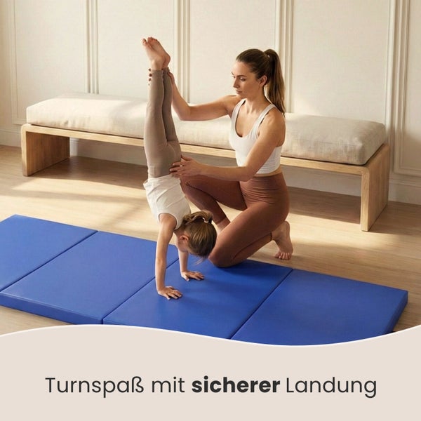 Turnmatte im Einsatz: Eine Frau hilft einem Kind beim Handstand.