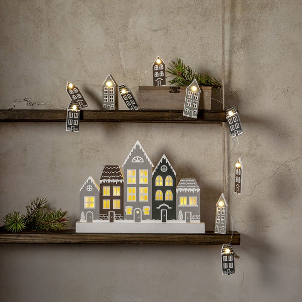 Dekorative Häuserlichterkette und beleuchtete Häuser auf Holzregalen