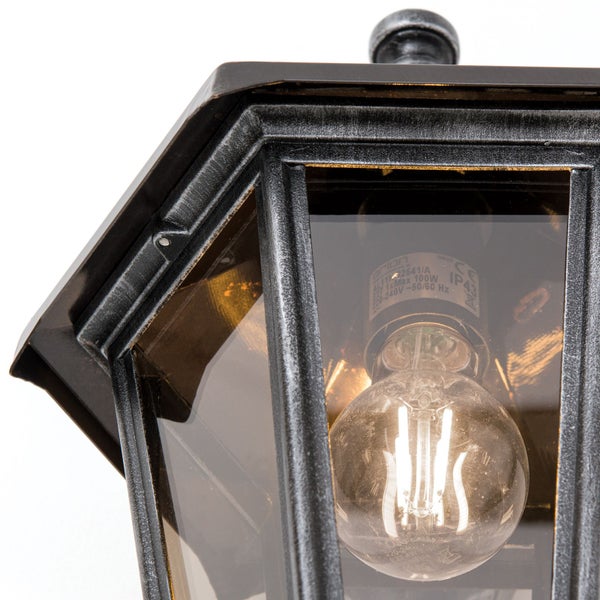 Detailansicht einer Außenleuchte im Laternen-Stil mit Glas und brennendem Filament-Leuchtmittel in Antik-Optik.