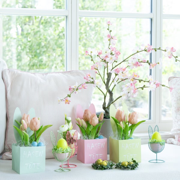 Dekorative Osterdekoration mit Blumen, Tulpen und Hasenmotiven vor einem Fenster
