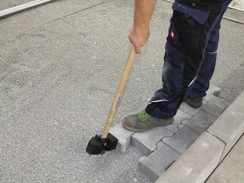 Pflasterarbeiten mit Gummihammer und Pflastersteinen