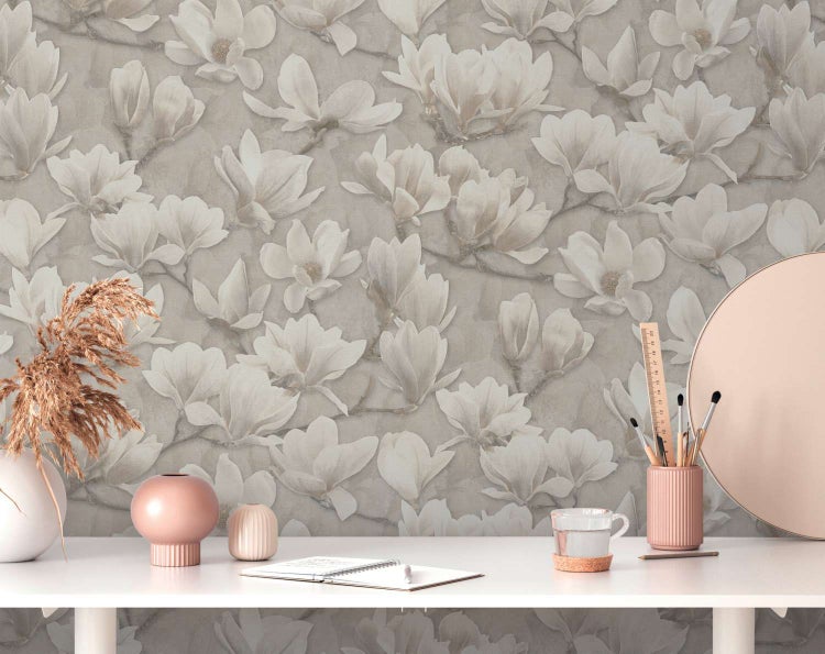 Vliestapete mit floralem Magnolienmuster in modernem Design an einer Wand hinter einem Schreibtisch mit Dekorationsobjekten.
