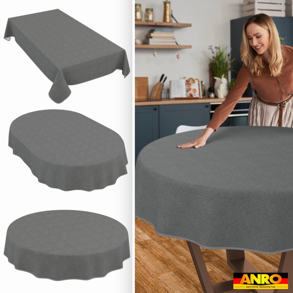 Graue Tischdecken in rechteckiger, ovaler und runder Form; Frau streicht Decke in einer Küche glatt. ANRO DEUTSCHE MANUFAKTUR Logo.
