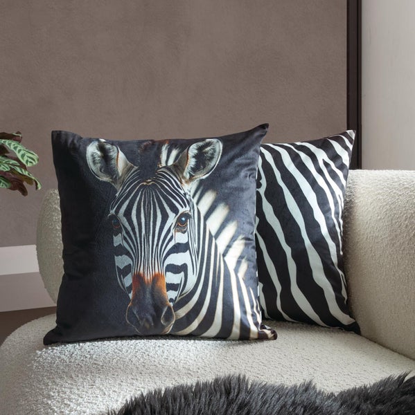 Zwei quadratische Dekokissen mit Zebramotiv auf einem hellen Sofa