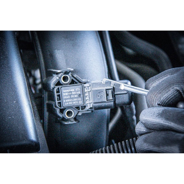 Ein Mechaniker mit Handschuhen demontiert einen Luftmassensensor mit Werkzeug.