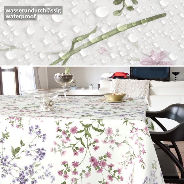 Wasserundurchlässige Tischdecke mit Blumenmuster in einem hellen Wohnzimmer. Nahaufnahme zeigt Wassertropfen auf der Oberfläche.