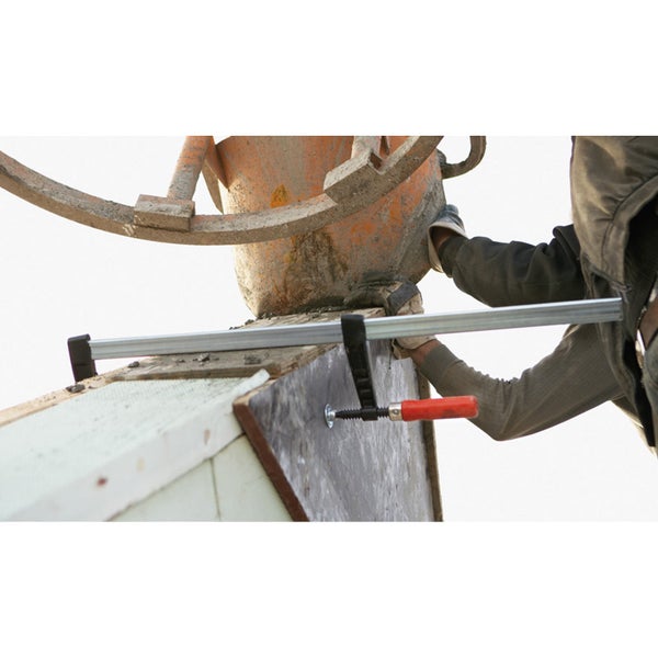 Handwerker mit Schraubzwinge und Betonmischer