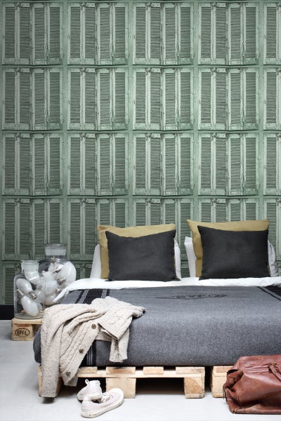 Schlafzimmer mit Wandtapete, Bett aus Paletten und dekorativen Elementen